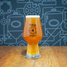 Load image into Gallery viewer, A pint glass filled with amber beer, standing on a wooden tabletop against a dark blue wall with white industrial line drawings. The glass has a visible logo reading PortSante and Cluster 12.
